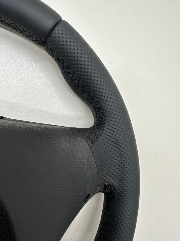 Back side view of a buttonless BMW M Sport steering wheel for E90 E92 E87 E82 with black stitches upclose